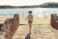 Boy in a swinsuit is standing by the beach