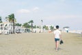 A boy in a T-shirt with sneakers on the sandy Mackenzie beach in Larnaca. Cyprus