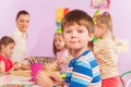Boy by the table in kindergarten class with mates Royalty Free Stock Photo