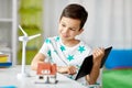 Boy with tablet, toy house and wind turbine Royalty Free Stock Photo