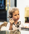 Boy take telephone receiver, play with antique vintage rotary old landline hang up phone beautifully embossed gold