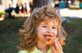 A boy with takes a bite of pizza. The child eat slice of pepperoni pizza. Funny kids face.