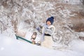 The boy is taking his teddy bear on a sledge to visit Santa Claus.