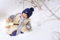 The boy is taking his teddy bear on a sledge to visit Santa Claus.