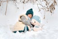 The boy is taking his teddy bear on a sledge to visit Santa Claus.