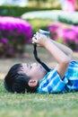 Boy taking photo by camera, exploring nature at park. Active lifestyle, curiosity, pursuing a hobby concept. Royalty Free Stock Photo