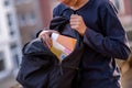 Boy taking textbooks out of the open schoolbag