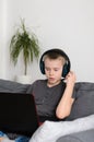 Boy talking on headphones and online video game on laptop computer at home. Child sitting and use pc Royalty Free Stock Photo