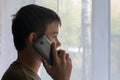 Boy is talking on the phone and looking out the window Royalty Free Stock Photo