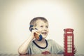 Boy talking on the phone and red telephone booth Royalty Free Stock Photo