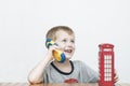 Boy talking on the phone and red telephone booth Royalty Free Stock Photo