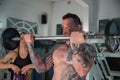 Boy with tattooed body does workout in the gym using weights, girl with kettlebell. Royalty Free Stock Photo