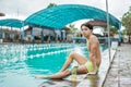 Boy teen swimmer in swimming trunks sitting resting with drinking bottle Royalty Free Stock Photo