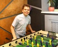 Boy teenager in a blue shirt plays in a table football with figures of football players of both teams in a wooden box in the Royalty Free Stock Photo