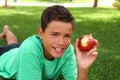 Boy teenager eating red apple on garden grass Royalty Free Stock Photo