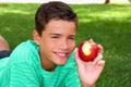 Boy teenager eating red apple on garden grass Royalty Free Stock Photo