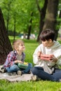 A boy and a teenager have a snack in the park after a game. A summer day in nature. Selective focus