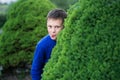 Boy teenager peeking out of a bush