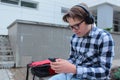 Boy teenager schoolboy or student in a shirt, smiles in glasses, listens to music on the phone Royalty Free Stock Photo