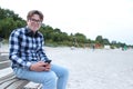 Boy teenager schoolboy or student in a shirt, smiles in glasses, listens to music on the phone Royalty Free Stock Photo