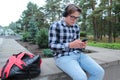 Boy teenager schoolboy or student in a shirt, smiles in glasses, listens to music on the phone Royalty Free Stock Photo