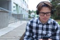 Boy teenager schoolboy or student in a shirt, smiles in glasses, listens to music on the phone Royalty Free Stock Photo