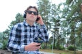 Boy teenager schoolboy or student in a shirt, smiles in glasses, listens to music on the phone Royalty Free Stock Photo