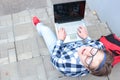 Boy teenager schoolboy or student is sitting on the stairs, working in the computer, wearing glasses, in a shirt, smiling, red b Royalty Free Stock Photo