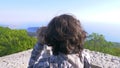 Boy teenager, traveler, looking through a telescope on top of a mountain.