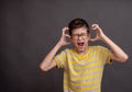 The boy is tense and very emotional, screaming in pain. He holds his hands to his head. Boy annoyed by loud noise having Royalty Free Stock Photo