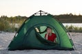 Boy in tent yawns. Early morning at campsite. Children`s tourism camping travel