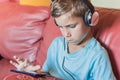 the boy is thinking and listening to music,playing,doing homework online with smartphone.Pupil in headphones Royalty Free Stock Photo