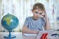 Boy thinking while looking at tablet while doing homework at home Royalty Free Stock Photo