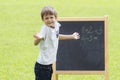 Boy thinking, writing and counting on blackboard. Green outdoor background Royalty Free Stock Photo