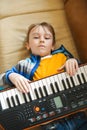 Boy tired of learning to play the synthesizer. Little dreamer want to be a musician