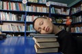 Boy tired sleeping on pile of books in library exausted on education Royalty Free Stock Photo