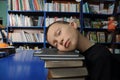 Boy tired sleeping on pile of books in library exausted of education Royalty Free Stock Photo