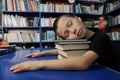 Boy tired sleeping on pile of books in library exausted to learning Royalty Free Stock Photo