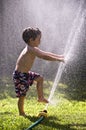 Boy toes fingers in sprinkler