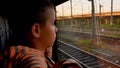A boy in a train car looks out the window at the rails and bridges he passes Royalty Free Stock Photo