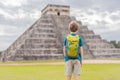 Boy traveler, tourists observing the old pyramid and temple of the castle of the Mayan architecture known as Chichen