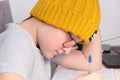 A boy in a trendy yellow knitted hat sitting by the table at home and doing homework Royalty Free Stock Photo