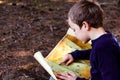 Boy trying to read an old travel map  lost in a forest  in search of adventure Royalty Free Stock Photo