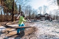 Boy turns carousel on playground in deep autumn park