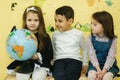 Boy with two girls look at the globe and search different continets and coutries Royalty Free Stock Photo