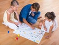 Boy and two girls playing at board game indoors Royalty Free Stock Photo