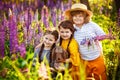 A boy and two girls with a puppy in a field with tall blue-purple flowers, a summer landscape. Children and a pet in the field of Royalty Free Stock Photo