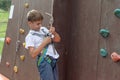 A boy unhooking a safety rope after descending a climbing wall at a sports park climbing wall Royalty Free Stock Photo