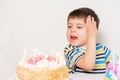 The boy is upset, celebrating his birthday, crying sitting at the table with a cake, a place for text. Royalty Free Stock Photo