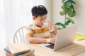 Boy use laptop for lessons. Drink water. Study home during quarantine
